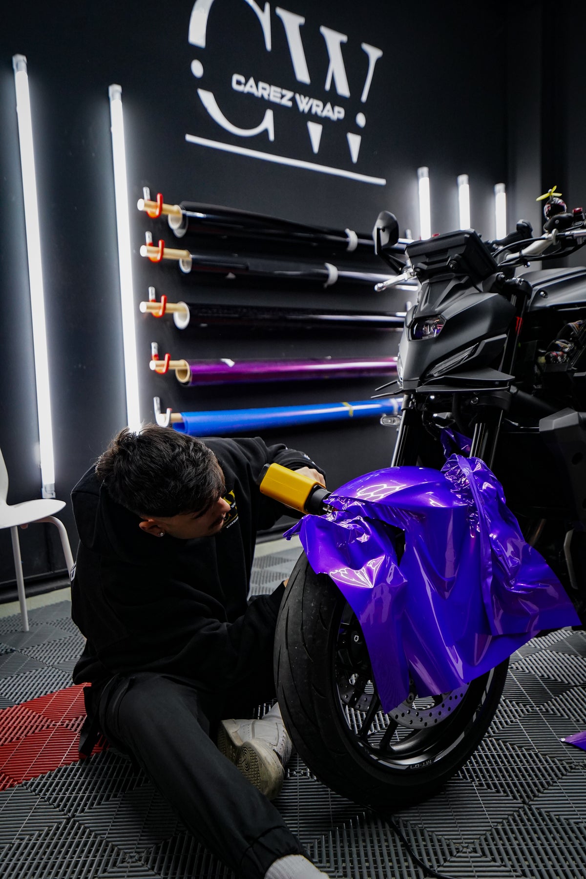 Professional fitting of a vinyl graphics kit on a motorcycle at the Carez Designs workshop